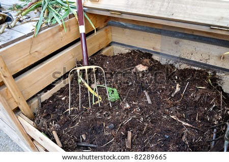open compost bin with garden fork