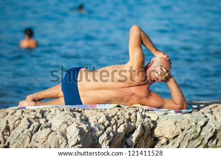 SPLIT, CROATIA - AUGUST 25, 2012: Older man sunning at he beach on August 25, 2012 in Split, Croatia. Split is the second largest city in Croatia.