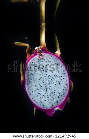 Sliced dragon fruit in water on black background