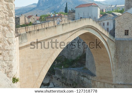 MOSTAR, BOSNIA - AUGUST 10: Man climbing the old Mostar bridge on August 10, 2012 in Mostar, Bosnia. The old bridge is a reconstruction of a 16th century Ottoman bridge in the city of Mostar.