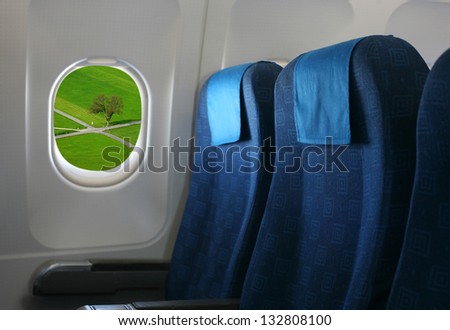 Airplane seat and window inside an aircraft with view of crossroad in field