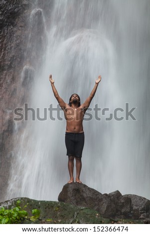Man at waterfall raising his hands in feeling closer to nature