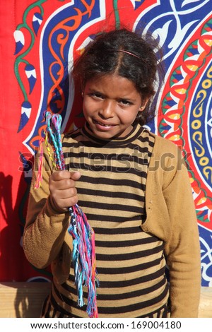 DAHAB - JANUARY 23. Young street seller showing off her bracelets in Dahab, Egypt. It provides income for their families.