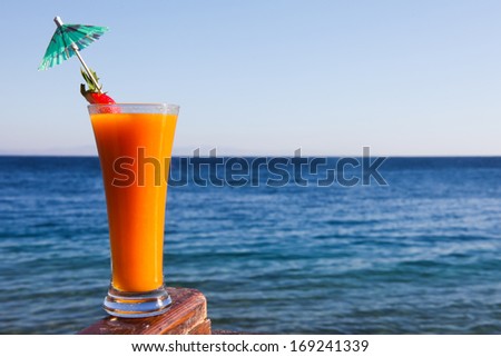 Long drink glass with a cocktail umbrella, garnished with strawberry against Red Sea in the Sinai region of Egypt