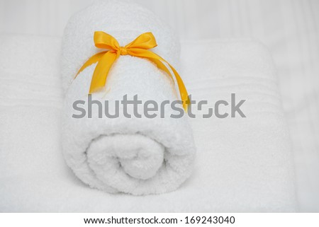 White towel with yellow ribbon folded on white sheets