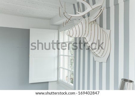 Decorative deer head on the wall covered in striped wallpaper.