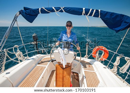 Young woman standing at the helm of a boat against a blue sky