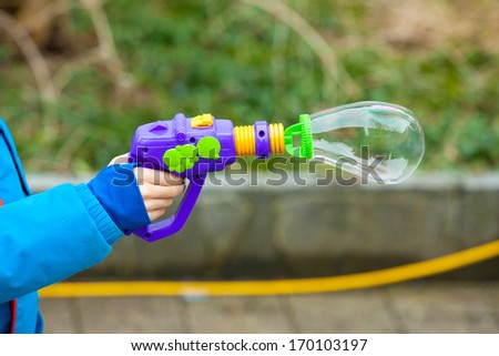 Child hand holding the soap bubble gun