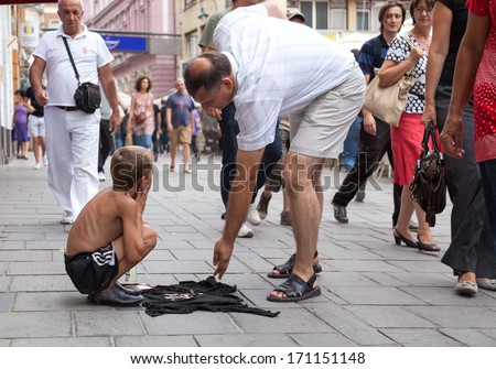 SARAJEVO, BOSNIA AND HERZEGOVINA - AUG 11: Sevdalija Osmanovic, 10 years old, sings on street to bypassers on August 11, 2012 in Sarajevo, B&H. He sings in order to provide money for his family.