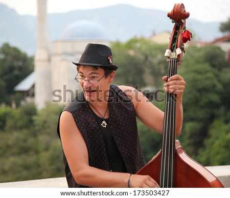 MOSTAR, BOSNIA AND HERZEGOVINA - AUGUST 9, 2012: Street musician plays double bass. The streets of Mostar are the stage of the Arts Festival.