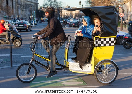 PARIS, FRANCE - JANUARY 6, 2012: Tourists driving in bicycle taxi and taking photos.