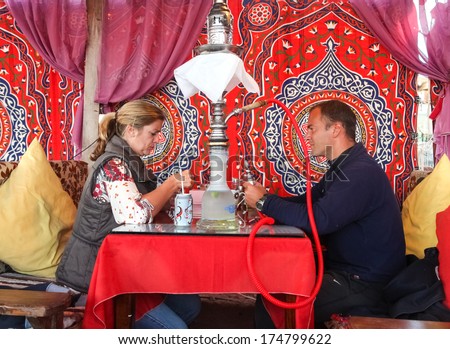 DAHAB, EGYPT - JANUARY 24, 2011: Couple sitting in the oriental bar with nargile at table. These water-pipes allow you to smoke flavoured tobacco as it is bubbled through water.