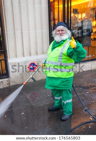 PARIS, FRANCE - JANUARY 4, 2012: Elderly worker washes street with mini wash. Paris is one of the very few cities in the world with a dual water system.