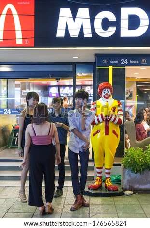 BANGKOK, THAILAND - JANUARY 9, 2012: Young local people stand in front of the McDonald\'s Restaurant at night. There are over 160 McDonald\'s restaurants in Thailand.