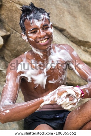 RAVANA FALLS, SRI LANKA - MARCH 2, 2014: Local boy covered with soap at Ravana falls, popular sightseeing attraction and one of the widest falls in the country.