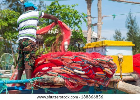 WELIGAMA, SRI LANKA - MARCH 7, 2014: Fisherman preparing fishing net on a boat. Tourism and fishing are two main business in this town.