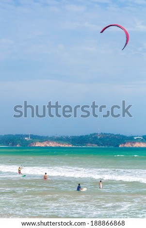 WELIGAMA, SRI LANKA - MARCH 7, 2014: Tourists swimming and kitesurfing in the sea. Tourism and fishing are two main business in this town.