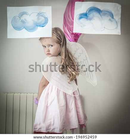 Young girl dressed as angel, with wings and painted clouds.