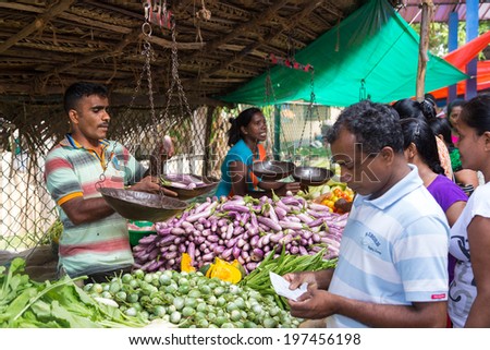 HIKKADUWA, SRI LANKA - FEBRUARY 23, 2014: Local street vendor selling vegetables. The Sunday market is great way to see Hikkaduwa\'s local life come alive along with fresh produce and local delicacy