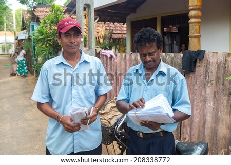 WELIGAMA, SRI LANKA - MARCH 8, 2014: Two postmen delivering post to local people. Sri Lanka Posts has been in existence for more than 209 years and employs more than 17,000 employees.
