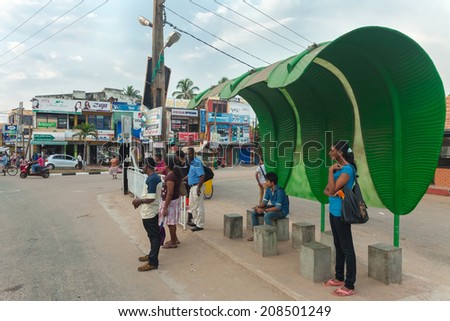 HIKKADUWA, SRI LANKA - FEBRUARY 22, 2014: Local people at banana leaf bus stand waiting for bus. Buses are the Sri Lankan principal mode of public transport.