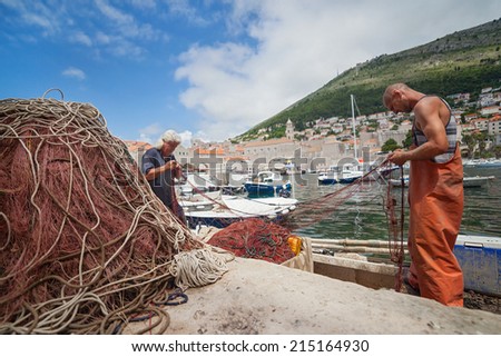 DUBROVNIK, CROATIA - MAY 26, 2014: Local fishermen in city port holding fishing net. Thanks to local fishermen Dubrovnik is brimming with fresh seafood.