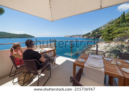 DUBROVNIK, CROATIA - MAY 28, 2014: Couple sitting and admiring stunning view over the Adriatic sea from the terrace of Villa Dubrovnik, one of Dubrovnik\'s most exclusive hotel and restaurant.