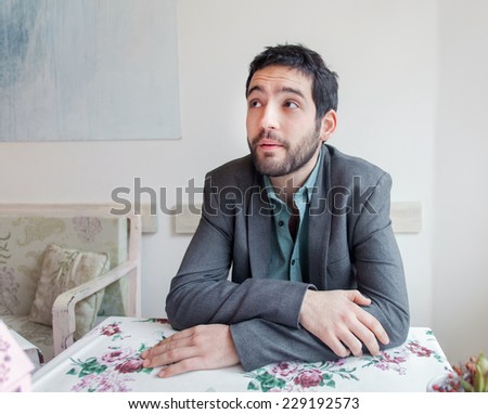Young man wearing jacket sitting in restaurant.