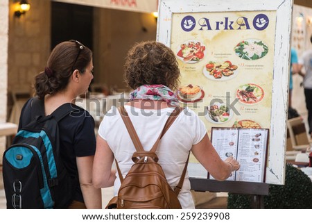 DUBROVNIK, CROATIA - MAY 28, 2014: Tourists looking at menu in front of the restaurant terrace. Dubrovnik has many restaurants which offer traditional Dalmatian cuisine and some great wine lists.