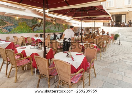 DUBROVNIK, CROATIA - MAY 26, 2014: Waiter setting up  tables at restaurant terrace. Dubrovnik has many restaurants which offer traditional Dalmatian cuisine and some great wine lists.