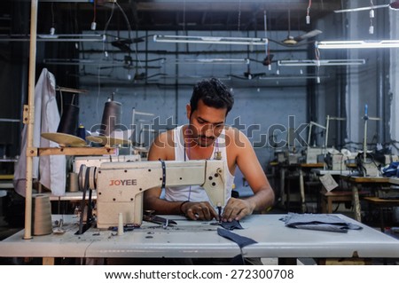 MUMBAI, INDIA - 12 JANUARY 2015: Indian worker sowing in a clothing factory in Dharavi slum
