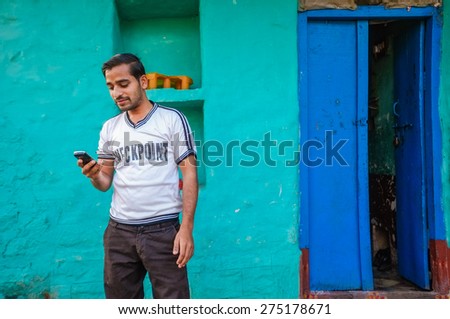 KAMALAPURAM, INDIA - 02 FEBRUARY 2015: Indian man looking at this mobile phone outside his home