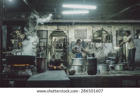 JODHPUR, INDIA - 07 FEBRUARY 2015: Two Indian workers in candy factory. Workers around India are underpaid, overworked and unhappy. Post-processed with added grain and texture.