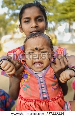 HAMPI, INDIA - 31 JANUARY 2015: Indian baby with bindi crying while being held by family member