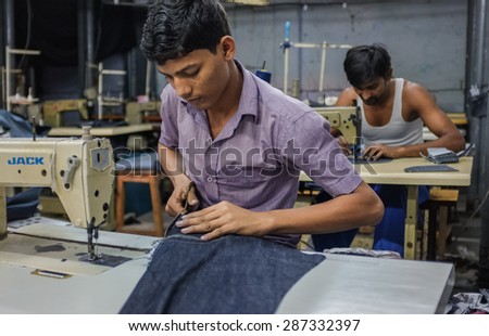MUMBAI, INDIA - 12 JANUARY 2015: Indian workers sewing in a clothing factory in Dharavi slum