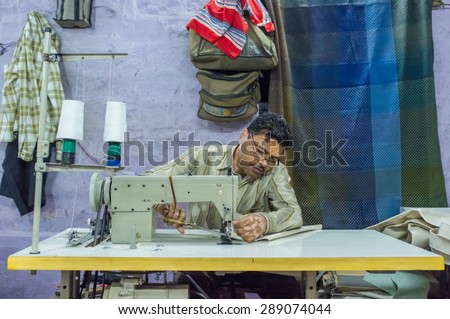JODHPUR, INDIA - 10 FEBRUARY 2015: Tailor at work in textile factory after working hours.