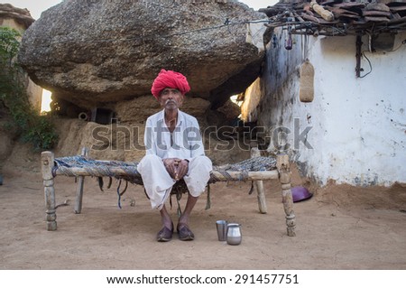GODWAR REGION, INDIA - 13 FEBRUARY 2015: Elderly Rabari tribesman sits on bed in courtyard of home. Rabari or Rewari are an Indian community in the state of Gujarat.