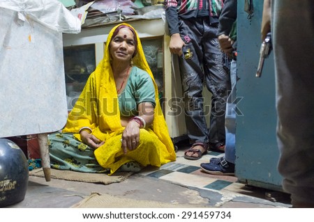 JODHPUR, INDIA - 16 FEBRUARY 2015: Woman sitting on floor of store while children stand next to her holding toy guns.