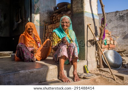 GODWAR REGION, INDIA - 13 FEBRUARY 2015: Two elderly Indian woman in sari\'s with covered heads sit in doorway of home.