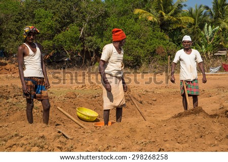 GOA, INDIA - 26 JANUARY 2015: Two elderly workers and one young adult dig soil in field