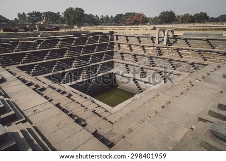 HAMPI, INDIA - 30 JANUARY 2015: Ruins of Hampi are a UNESCO World Heritage Site. Stepped tank. Post-processed with grain, texture and colour effect.