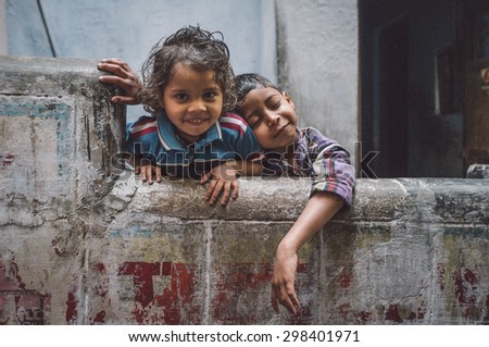 VARANASI, INDIA - 20 FEBRUARY 2015: Two siblings enjoy each others company. Brother resting on sisters sholder. Post-processed with grain, texture and colour effect.