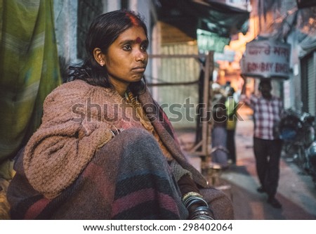 VARANASI, INDIA - 25 FEBRUARY 2015: Indian homeless woman sitting in street. Post-processed with grain, texture and colour effect.