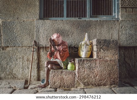 HAMPI, INDIA - 28 JANUARY 2015: Elderly Indian man begs in Virupaksha Temple, part of Group of Monuments at Hampi. UNESCO World Heritage Site. Post-processed with grain, texture and colour effect.