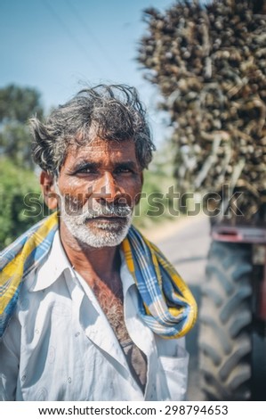 HAMPI, INDIA - 28 JANUARY 2015: Portrait of Indian worker next to truck loaded with sugarcane. Post-processed with grain, texture and colour effect.