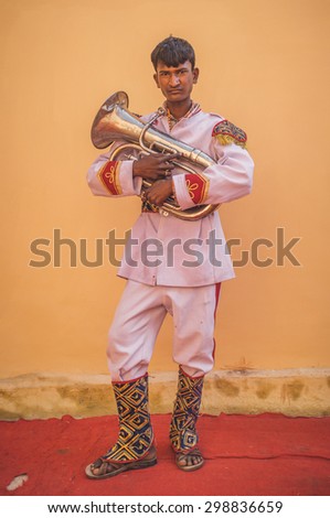 GODWAR REGION, INDIA - 15 FEBRUARY 2015: Young Indian musician dressed in wedding ceremony outfit holds trumpet. Post-processed with grain, texture and colour effect.