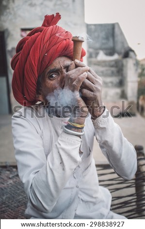 GODWAR REGION, INDIA - 12 FEBRUARY 2015: Rabari tribesman smokes chillum. Post-processed with grain, texture and colour effect.