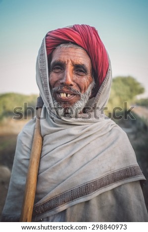 GODWAR REGION, INDIA - 14 FEBRUARY 2015: Elderly Rabari tribesman stands with ax on sholder. Post-processed with grain, texture and colour effect.