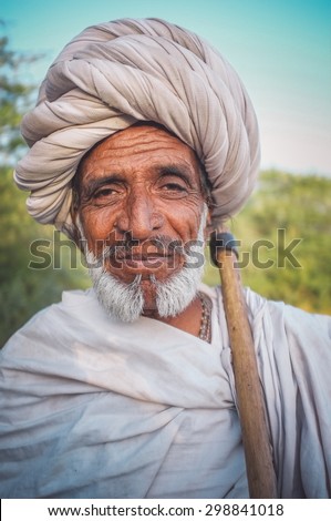 GODWAR REGION, INDIA - 14 FEBRUARY 2015: Elderly Rabari tribesman with white turban and blanket around the shoulders and ax. Post-processed with grain, texture and colour effect.