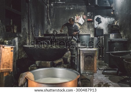 VARANASI, INDIA - 19 FEBRUARY 2015: Indian cook makes last meal after long work day. Post-processed with grain, texture and colour effect.